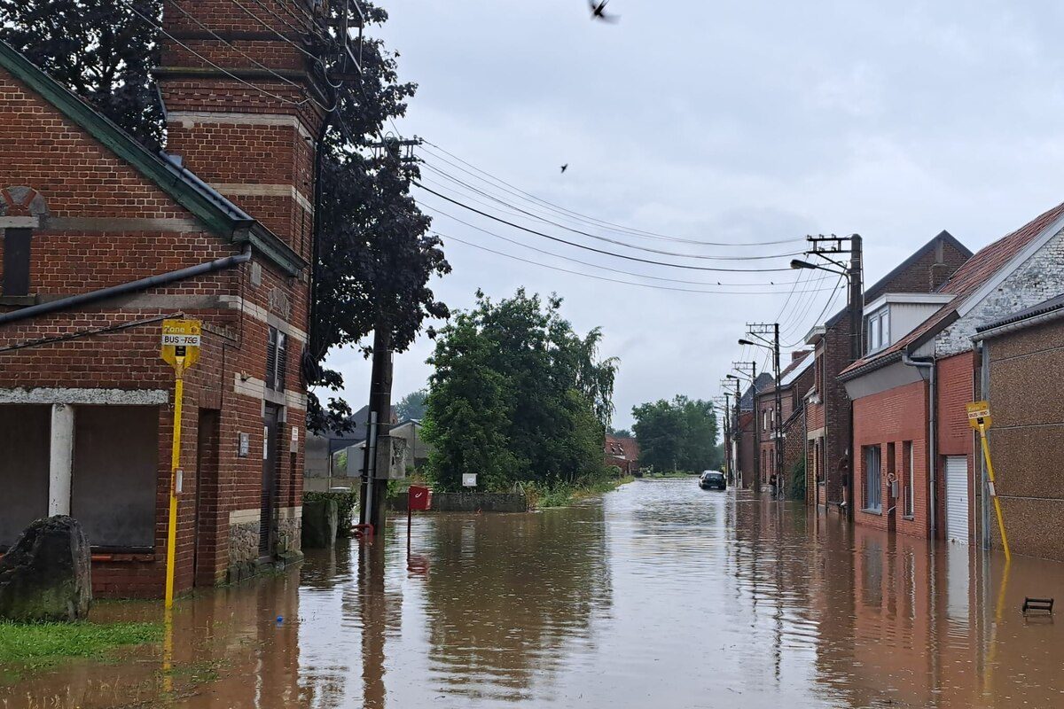 Rue de village inondée : l'eau recouvre la chaussée jusqu'au seuil des maisons, un camion-citerne intervient